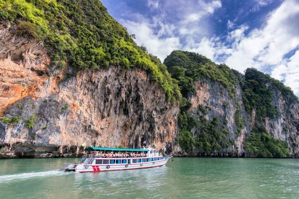 A boat cruise offers breathtaking views of lush cliffs under a bright blue sky.